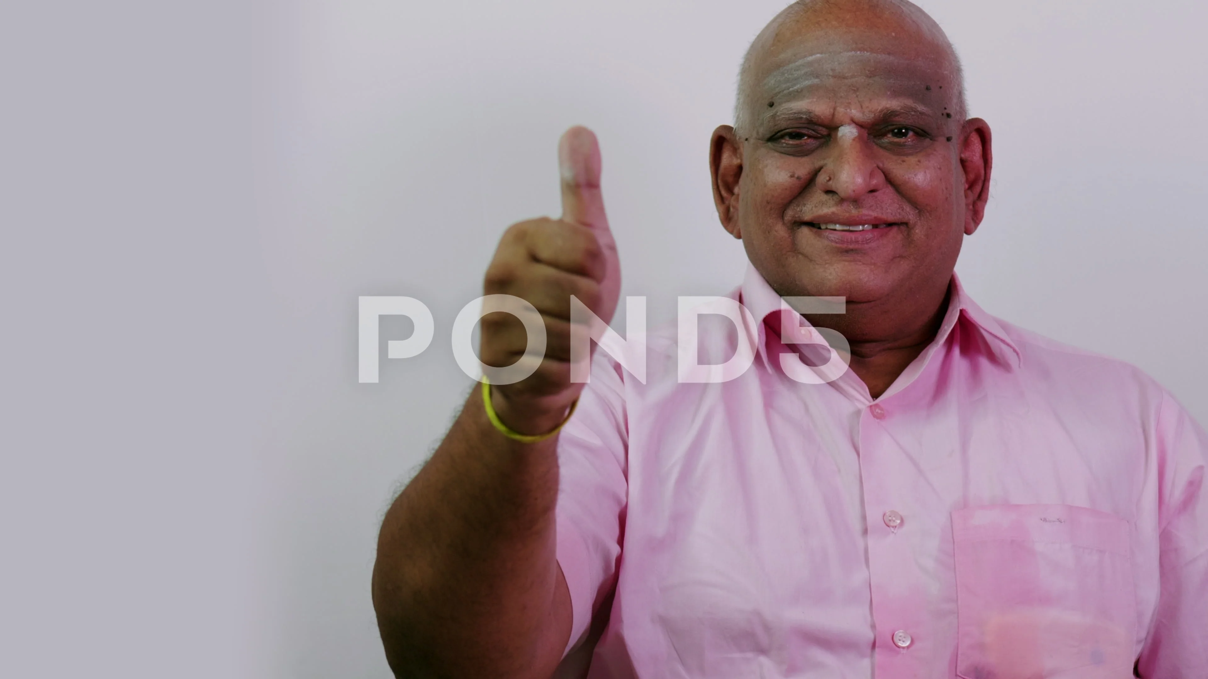 A south indian old fat man showing thumbs up in plain background