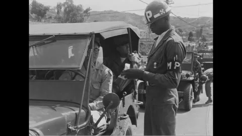 SOUTH KOREA - 1952: Document check - MP checks papers beside an occupied jeep Stock Footage 344499340
