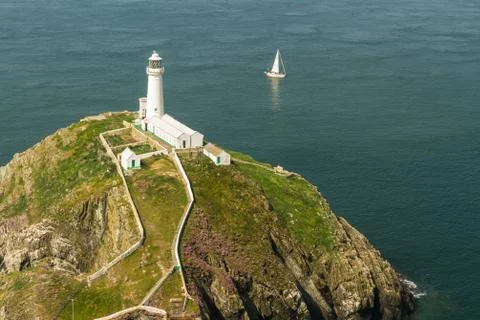 South Stack lighthouse, Anglesey, with white sailing yacht. Stock Photos