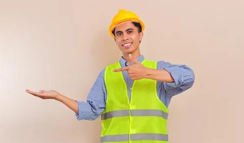 Southeast Asian construction worker in hard hat and safety vest smiling whi.. Stock Photos