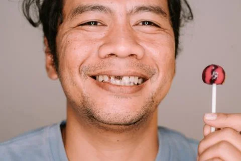 Southeast Asian man with a missing tooth eating candy, Stock Photos