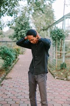 "Southeast Asian man standing while touching his hair with a casual expressio Stock-Fotos