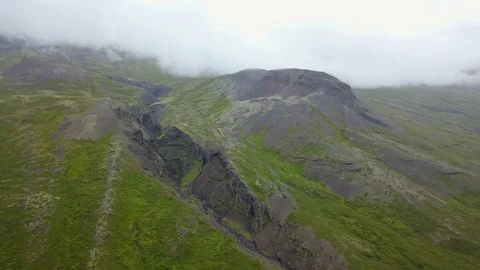 Southern Icelandic drone shot of large ravine on mountain side with clouds Stock Footage 84443473