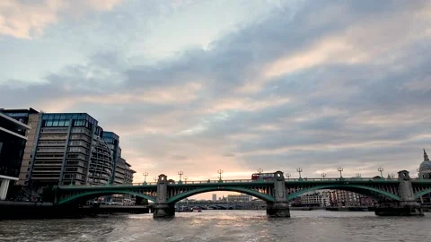 Southwark Bridge spans the River Thames at golden hour as a red bus crosses and Stock Footage 342186231