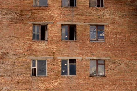 Soviet architecture. A collapsing brick wall with broken and open windows. Stock Photos