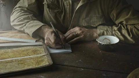 Soviet Army soldier analyzes map and draws up action plan sitting in abandoned Stock Photos