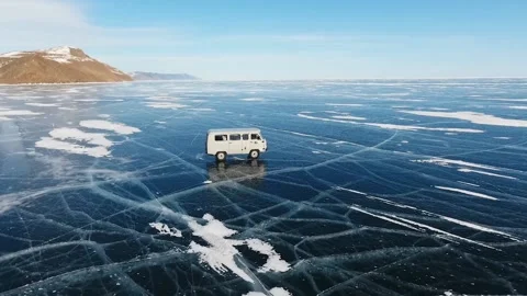 Soviet car UAZ rides on the icy surface of frozen Baikal lake. Fly around. Stock Footage 140962773