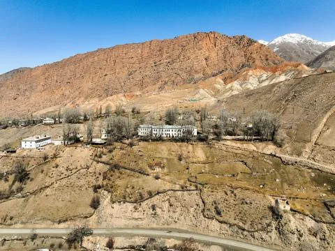 Soviet-era central building in Ming-Kush on a hillside beneath red mountains Stock Photos