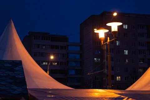 Soviet panel houses in the distance in the evening. A burning street lamp Stock Photos