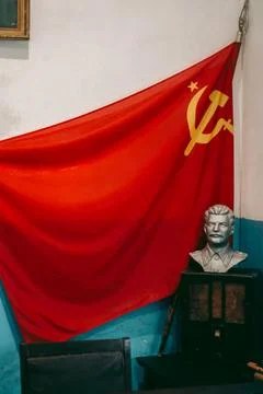 Soviet red flag with a sickle and a hammer and a bust of Lenin in the office Stock Photos