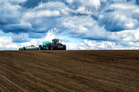 Sowing work in the field in spring. Tractor with seeder Stock Photos