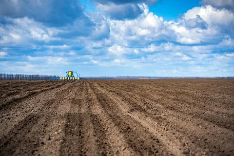 Sowing work in the field in spring. Tractor with seeder Stock Photos