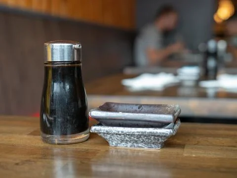Soy sauce container and stack of dishes in a restaurant with diners Stock Photos