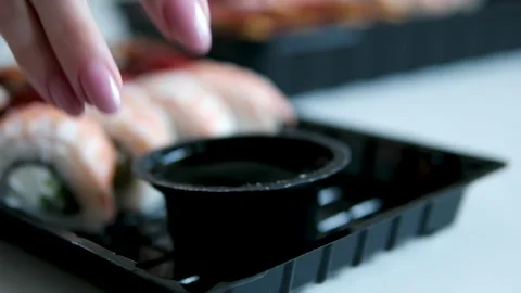 Soy sauce in plastic container near black sushi takeaway boxes delivery food Stock Footage 346190285