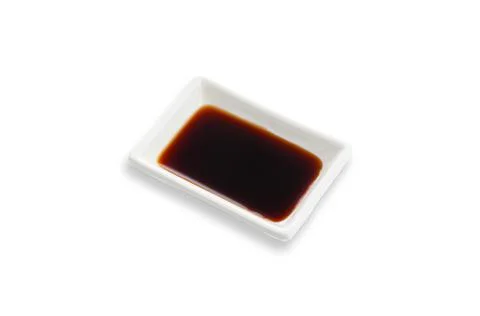 Soy sauce in a white rectangular gravy boat. Seasoning for sushi. White backg Stock Photos