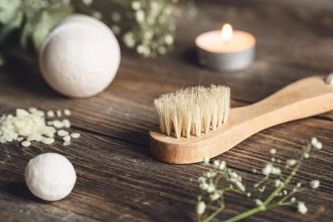 Spa composition with brush, candle and dried flowers on wooden surface. Stock Photos