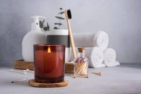 Spa composition with burning candle and bathroom accessories on grey backgrou Stock Photos
