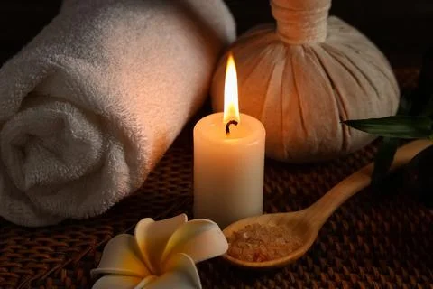 Spa composition with burning candle and spoon of sea salt on wicker mat as ba Stock Photos