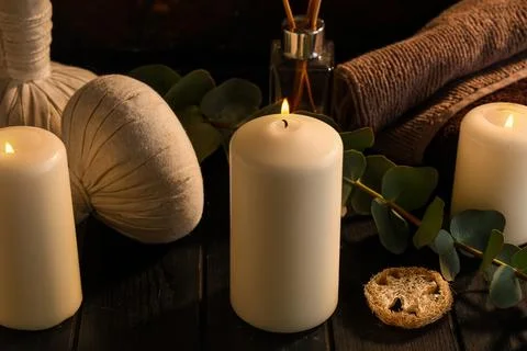 Spa composition with burning candles, herbal bags and green twig on black woo Stock Photos