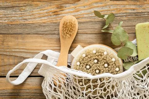 Spa composition with massage brushes and hygiene items in a mesh shopping bag. Stock Photos