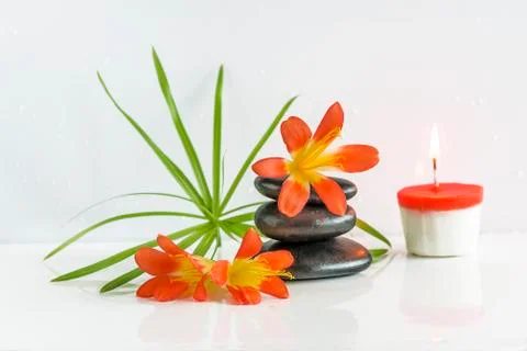 Spa composition. Pyramid of black massage stones, orange flowers and burning  Stock Photos