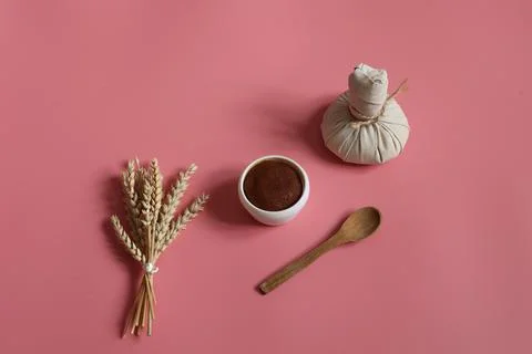 Spa composition with scrub, herbal bag and wooden spoon on a pink background. Stock Photos