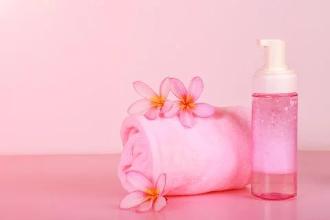 Spa composition with towel, flowers and bottle of soap on pink background Stock Illustration