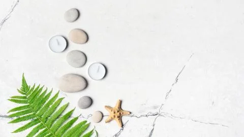 Spa concept. Top view of grey sea stones and aroma candles on white marble ba Foto stock