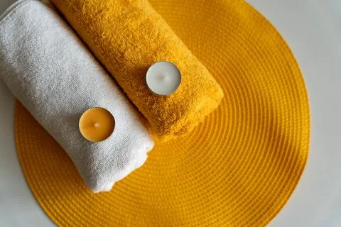 Spa concept. Two white and orange towels with candles on an orange rug. Welln Stock Photos