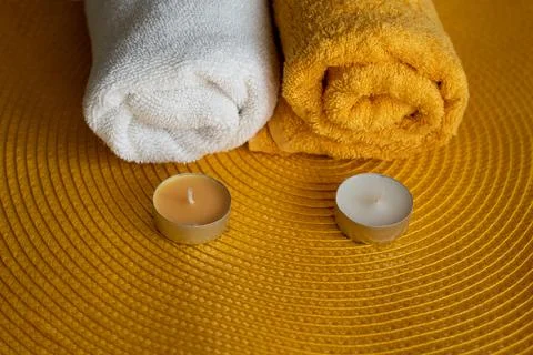 Spa concept. Two white and orange towels with candles on an orange rug. Welln Stock Photos