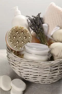Spa gift set of different luxury products in wicker basket on grey table, clo Stock Photos