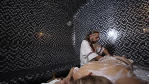 Spa master in a hammam performs a foam massage of female legs 動画素材 157971098