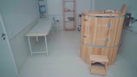 Spa room with cedar phytobarrel a stool is placed next to it, couch and a shelf Stock Footage 154002702