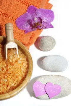 Spa set of orange bath salts, massage stones, towel and orchid flower Stock Photos