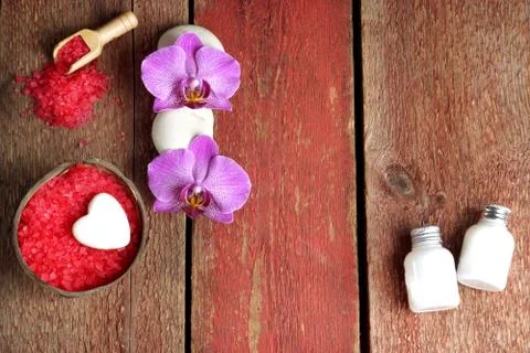 Spa set with red bath salt, orchid and towel flowers, lotion and soap on a wo Stock Photos