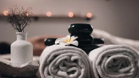 Spa setting featuring stacked black stones, rolled towels, and decorative Stock Footage 323962923