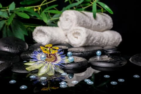 Spa setting of passiflora flower, branches, stacked towels, zen basalt ston.. Stock Photos
