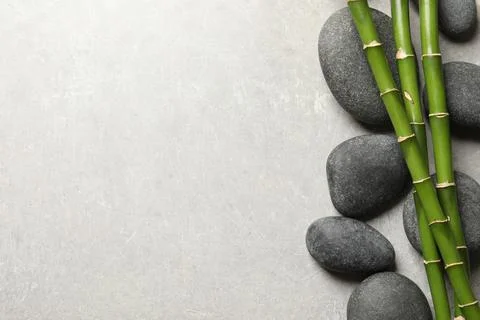Spa stones and bamboo stems on light grey table, flat lay. Space for text Stock Photos