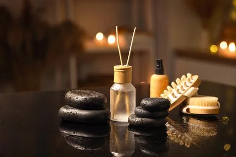 Spa stones with reed diffuser, cosmetic oil and massage brushes on table in d Stock Photos