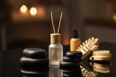 Spa stones with reed diffuser, cosmetic oil and massage brushes on table in d Stock Photos