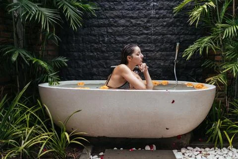 Spa surrounded by palm trees. at the stone wall stands a bath with water and Foto stock