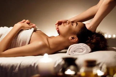 Spa treatment. Afro woman enjoying face massage Stock Photos