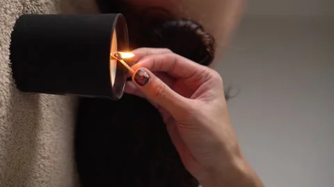 In spa. women's hands light scented candle in foreground with match Stock Footage 221434823