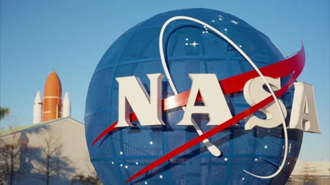 Space agency globe sign with rocket boosters in background on clear day Stock Footage 337913814