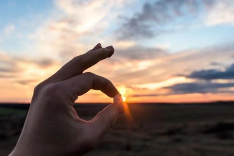 The space between the fingers of the hands at sunset. hand on sky background Stock Photos