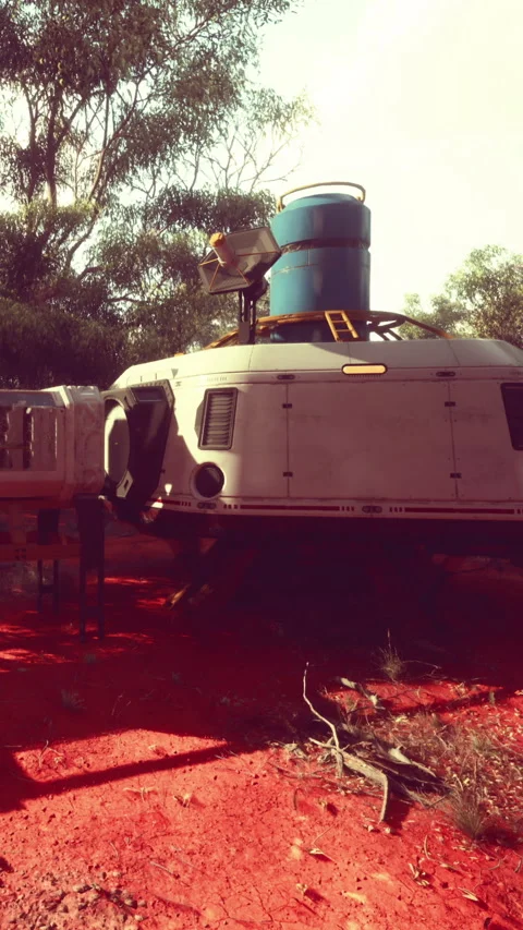 Space capsule resting on red ground with blue container in background Stock Footage 335356259