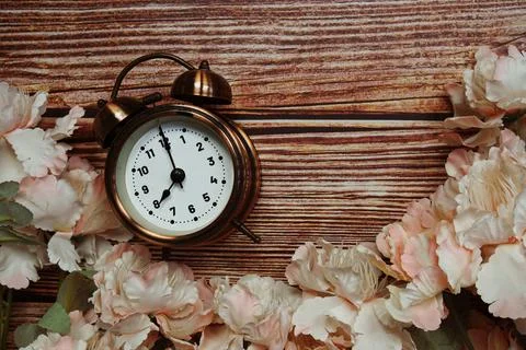 Space copy background with alarm clock and flower decoration on wooden back.. Stock Photos