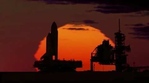 Space Shuttle on crawler silhouetted by sunset moving towards platform. Stock Footage 20455516