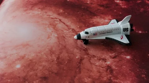 A space shuttle model on a red universe background slowly moves to the left.. Stock Footage 339409261