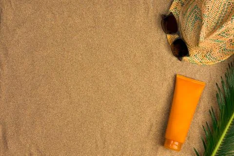 Space for text, beach theme on sand background. Hat, sunglasses, sunscreen on Stock Photos